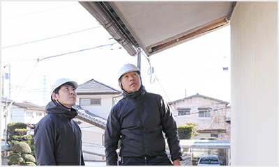 ヘルメット姿のスタッフが住宅の軒先を点検している様子